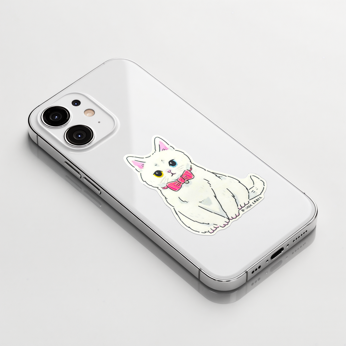 Elegant White Kitten Pink Bow ✦ B-Side Label Sticker on a white iPhone
