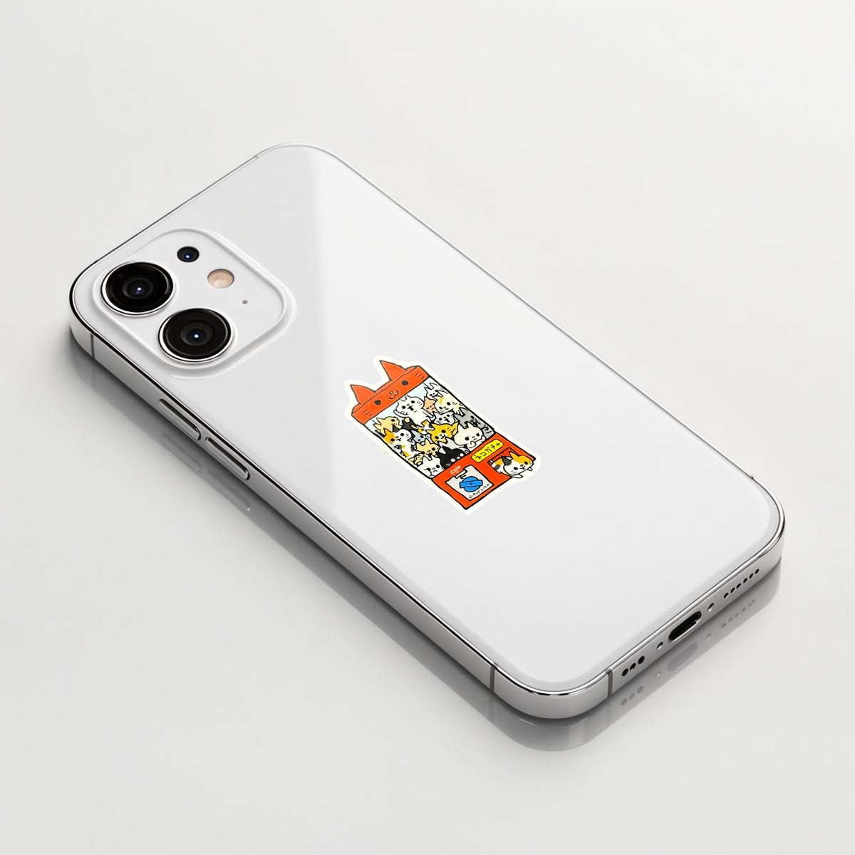 Cat Gatcha Machine sticker shown on a white iPhone; illustrative placement, not to scale.